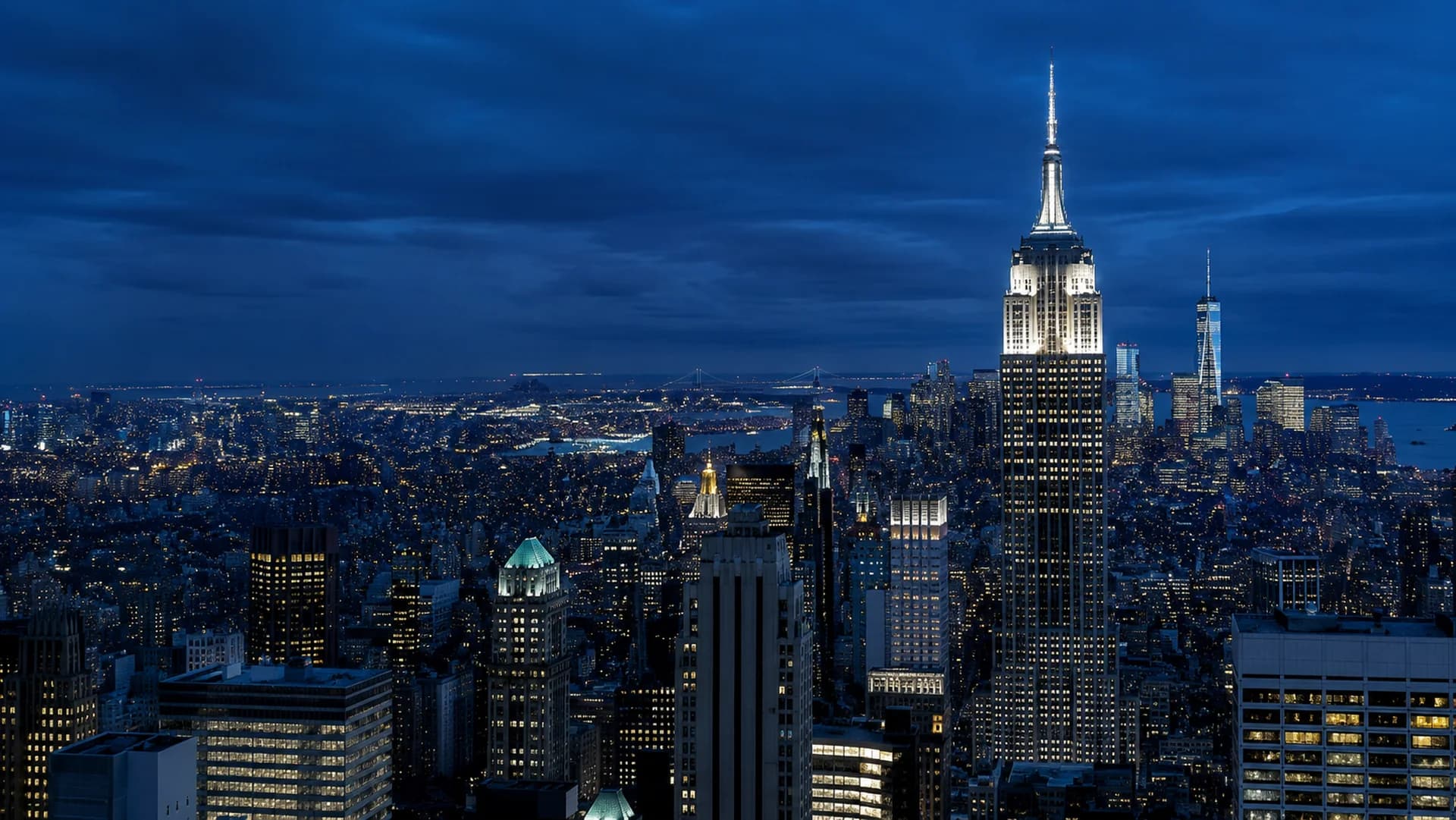 The New York City skyline at dusk, with the Empire State Building lit against a deep blue sky